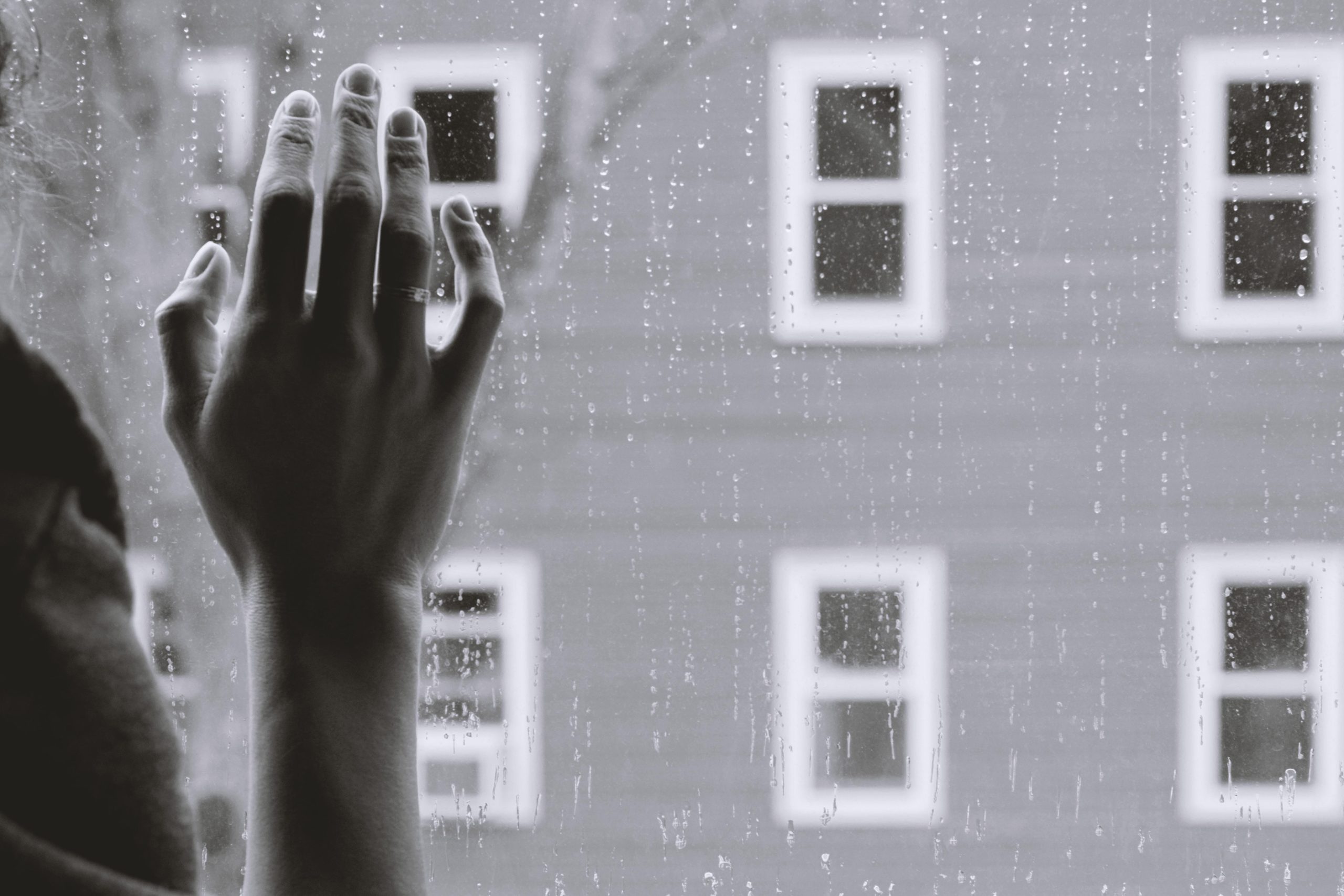 Hand on rainy window